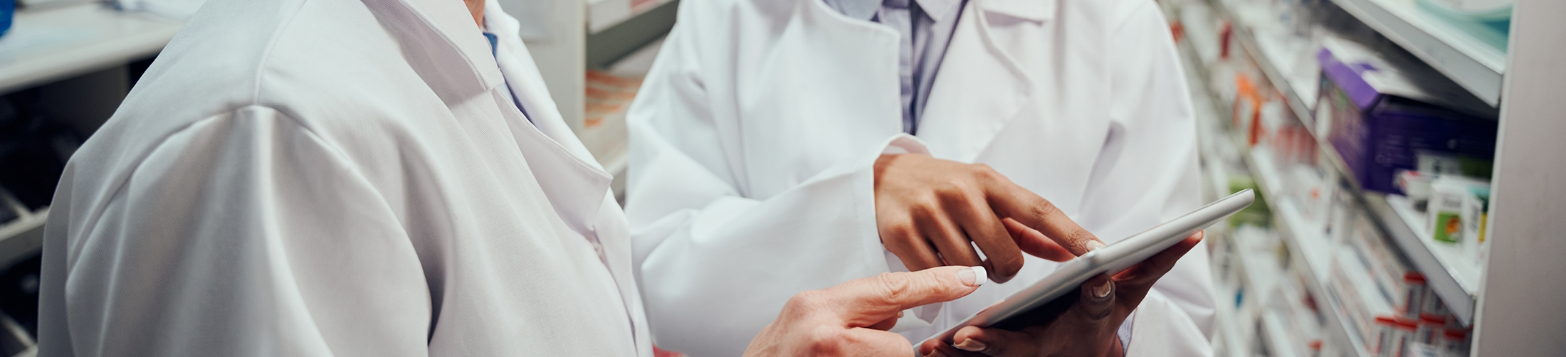 Zwei Personen in weißen Kitteln beraten sich mit Hilfe eines Tablets