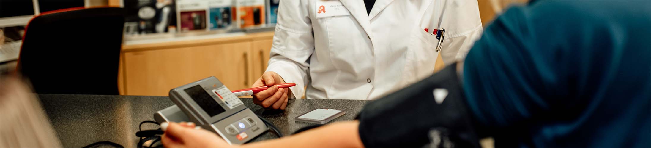 Angestellte führt beim Kunden eine Blutdruckmessung durch